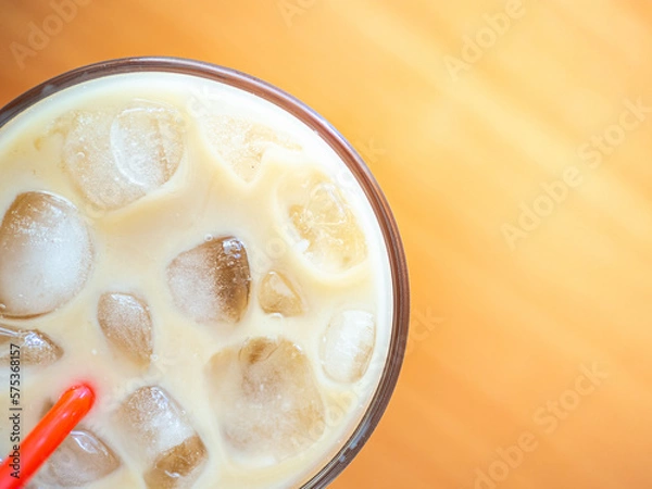 Fototapeta Ice coffee on a wood table with ice and red straw. Cold summer drink with red tube.Above close-up view flatlay