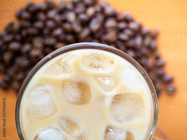 Fototapeta Ice coffee on a wood table with ice, coffe beans on background. Cold summer drink.Above close up view flatlay