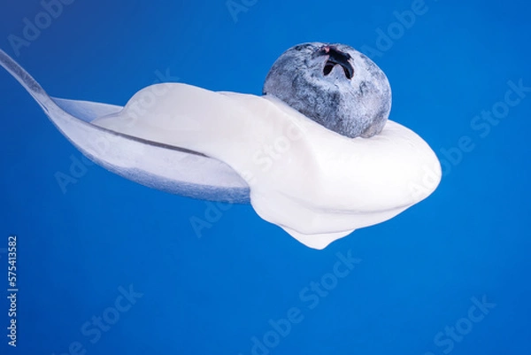 Obraz Spoon of blueberry yogurt on blue background. Spoon with yogurt and blueberry close up. Healthy food