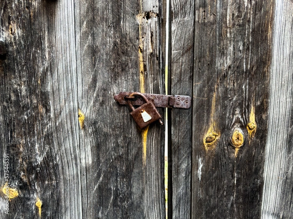 Fototapeta The old wooden door is closed with an old lock