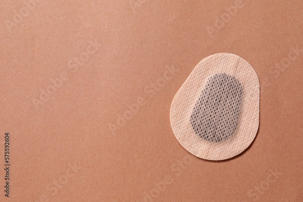 Fototapeta Contraceptive patch on light brown background, top view. Space for text