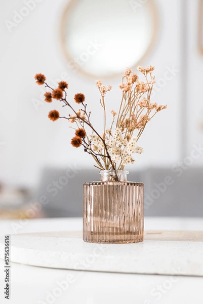 Obraz A pink design glass vase with dried wild flowers inside over a granite board.