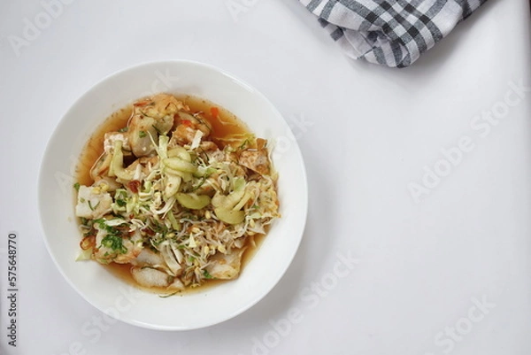Fototapeta Kupat tahu is a traditional Indonesian food consisting of ketupat and tofu in peanut sauce. Usually include rice cake, tofu, bean sprouts, brown sugar, and prawn crackers. Served in white plate.