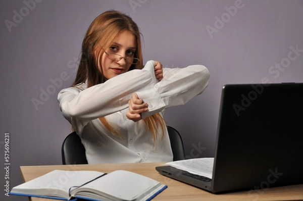 Fototapeta Portrait of an angry business woman sitting near the table and looking at the camera. Grumpiness and work concept