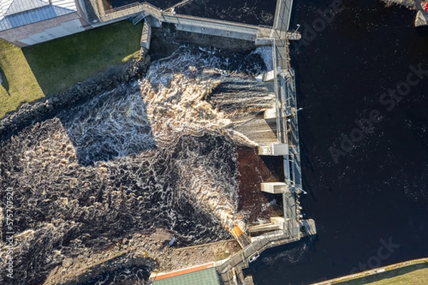 Fototapeta Aerial view on a big dam, barrage, weir in a city near a green area on a sunny day