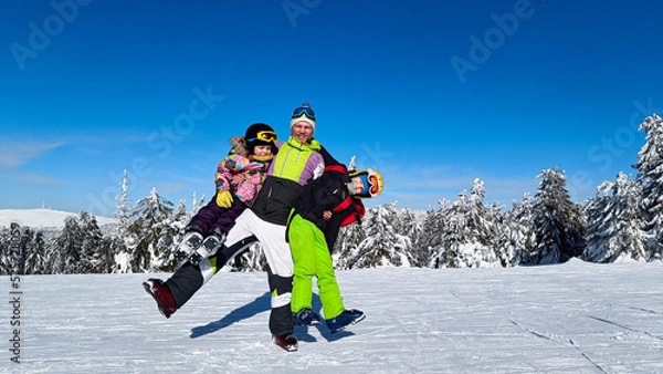 Obraz Dad with children on skiing in the mountains looking into the camera