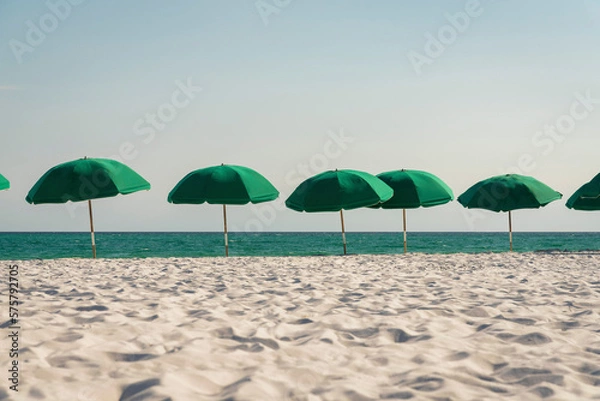 Obraz Outdoor green beach umbrellas on a white sand beach at Destin, Florida. There is a row of umbrellas at the front near the blue ocean under the clear sky at the background.