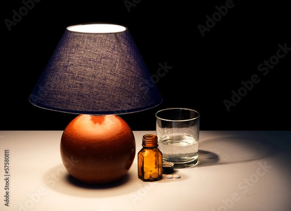 Fototapeta Bedside table lamp with tablets, water - insomnia maybe