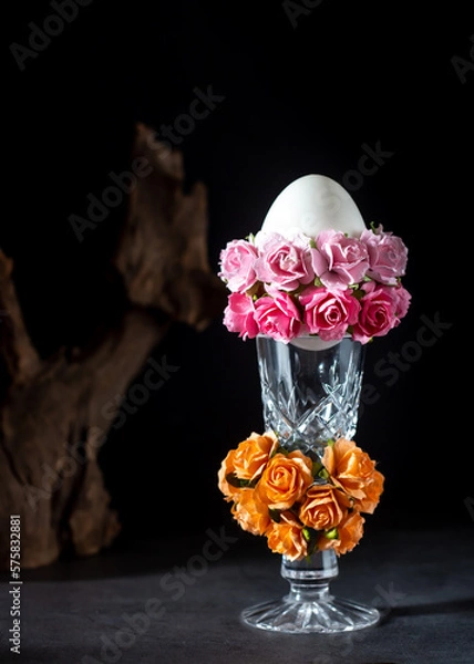 Fototapeta Easter egg in a glass vase with roses on black background