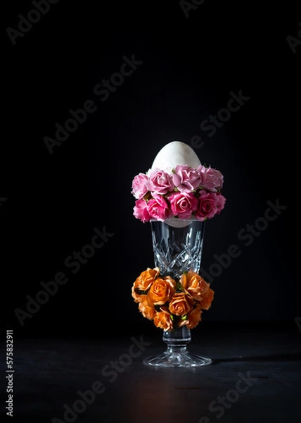 Fototapeta Easter egg in a glass vase with roses on a black background