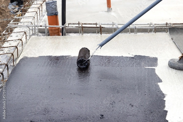 Obraz Worker applying a bituminous primer on a Concrete Slab Before Waterproofing