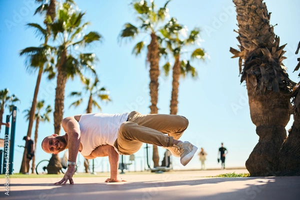 Fototapeta young guy making break dance moves outside in a park in a sunny day