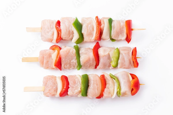 Obraz Top view.Uncooked mixed meat skewer with peppers.Raw turkey skewers with vegetables, peppers, onions on a white background.Skewers with pieces of raw meat, red, and green pepper, on white background.