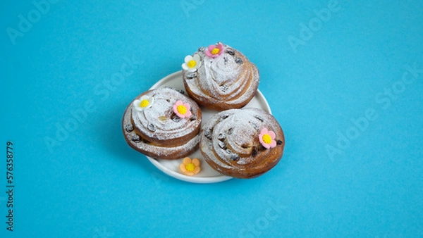 Fototapeta Easter eggs and decor on fresh buns with spirals with white icing sugar.