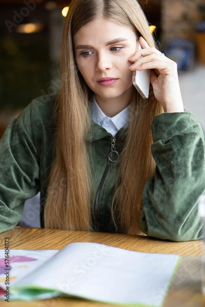 Fototapeta The girl is discussing a scientific project on the phone. Remote consultation.