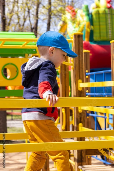 Fototapeta todler boy at the playground on a sunny spring day with space for text