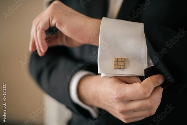 Fototapeta closeup of groom's hands and arms as he adjusts sleeve and cufflink