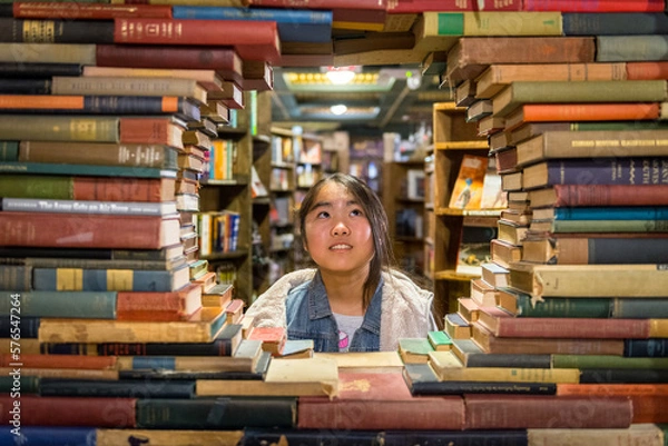 Obraz Young asian girl standing behind window created by stack of books