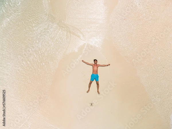 Obraz The guy lies on a sandy beach on a tropical island.