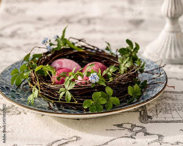 Fototapeta easter colored pink eggs in diy wreath from birch on blue plate with flowers