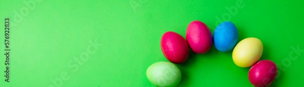 Fototapeta Green background and colored Easter eggs in the form of a rainbow. Copy space for text.