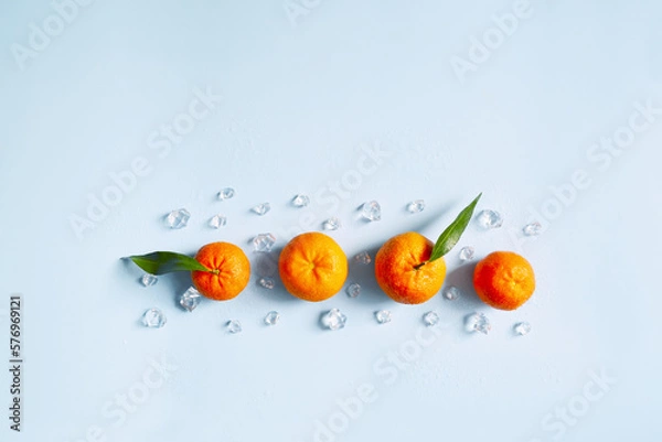 Fototapeta Frame, lay out ice cubes, mandarin and water drops on the blue background. Summer vibes. Cooling fresh humid template composition. Empty space for text on the top. Flyer, card, invitation.