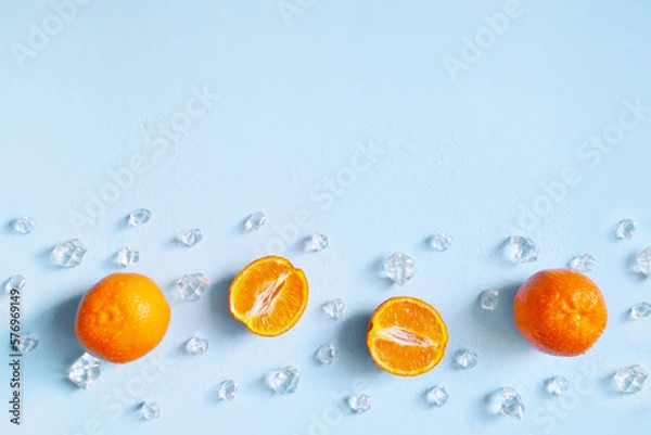 Fototapeta Frame, lay out ice cubes, mandarin and water drops on the blue background. Summer vibes. Cooling fresh humid template composition. Empty space for text on the top. Flyer, card, invitation.