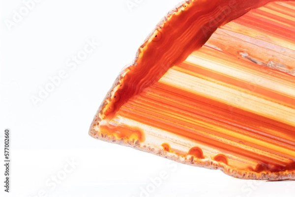 Fototapeta White, dark and light orange, red semi-transparent agate slice crystal, straight bands of silica chalcedony stone isolated on a white background surface with detail. Abstract crystal with copy space