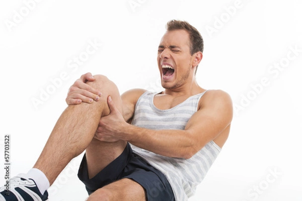 Obraz Man screaming from a pain in his knee. While isolated on white