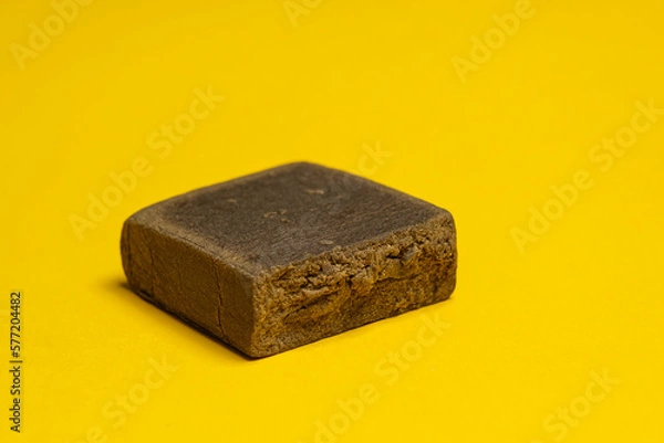 Fototapeta Hashish stick ready for sale on a yellow background. Medical marijuana extraction dry hashish cannabis pollen.