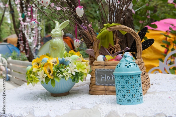 Fototapeta Easter still life in the garden. Bunny and colored eggs in wooden basket 