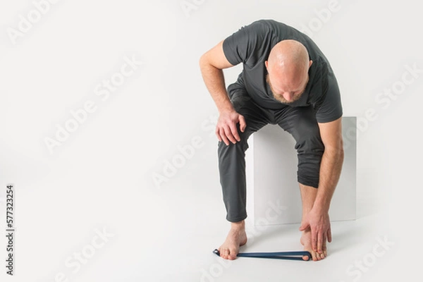 Fototapeta Bearded man is doing exercise with rubber . White background
