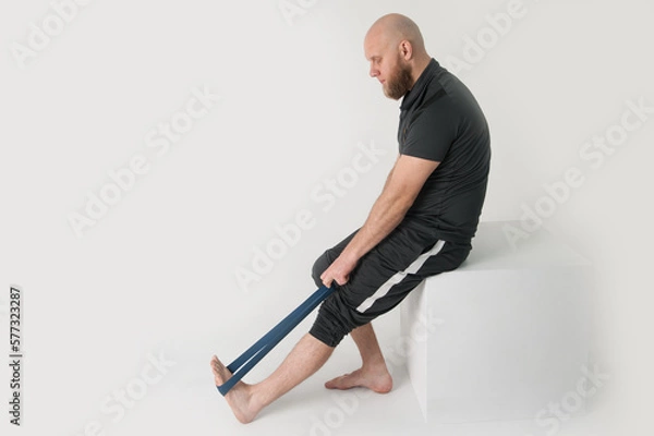 Fototapeta Bearded man is doing exercise with rubber . White background