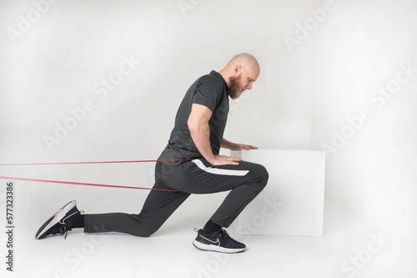 Fototapeta Bearded man is doing exercise with rubber . White background
