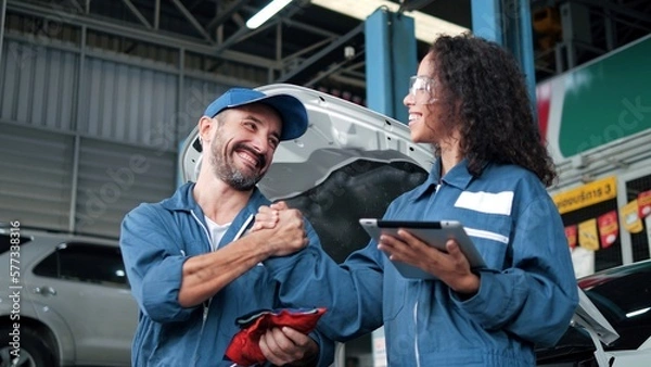 Obraz Two car mechanic team shaking hand at automobile service center. Repair service concept. Car repair and maintenance. Car mechanic working at automotive team service center