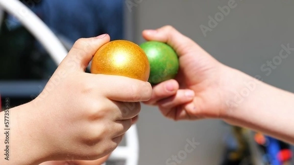 Fototapeta Two kind beat colorful green and orange Easter eggs outdoor. Seasonal tradition games in happy Easter holiday. Close up. Knocking eggs figh game.