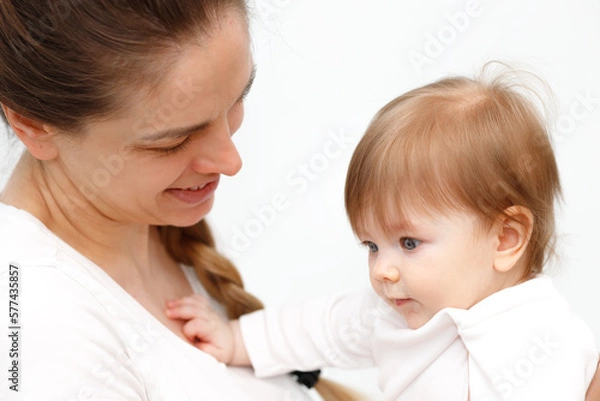 Fototapeta Bright portrait of happy mother holding infant child on hands. Mother hugging her little 6 months old baby.