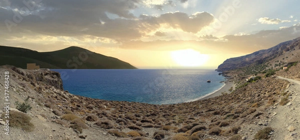 Fototapeta Mountain range on the beach of Greece on the island of Crete. Beautiful landscape with Mediterranean sea and cloudy sky at sunset.