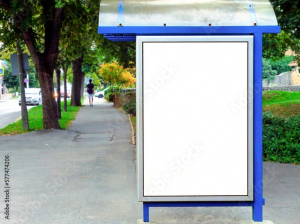 Fototapeta bus shelter at busstop. blank white lightbox. empty billboard ad placeholder. glass and aluminum structure. transit station. urban setting. city street background. asphalt sidewalk. base for mockup