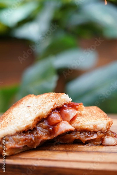 Fototapeta Sándwich de desayuno con tocino, queso y salsa de tomate sobre tabla de madera
