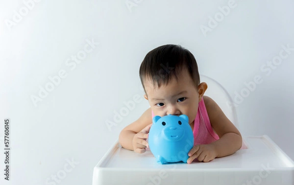 Fototapeta Asia baby boy saving money for future concept on white background, Happy baby with a piggy bank