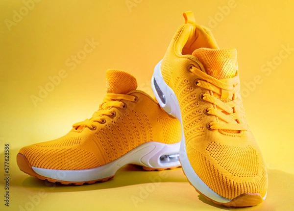 Obraz pair of yellow sneakers on yellow background. copy space