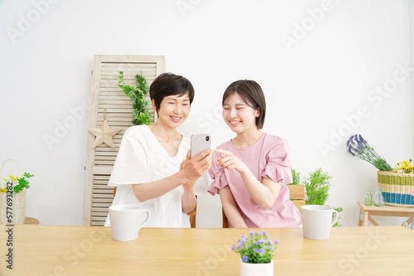 Fototapeta 家でスマホを使う母親と娘