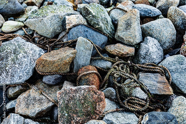 Fototapeta Old rope on the rocks at the sea shore, decorative background or texture