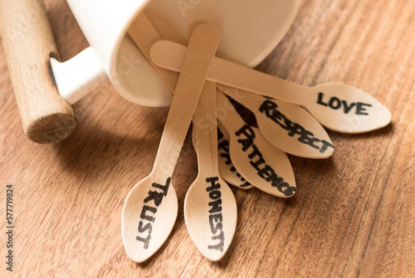 Fototapeta Bunch of  wooden spoons laying from a white coloured coffee mug each spoon hand written with words like love ,trust ,patience ,empathy ,honesty the essence of relationship in a wooden background