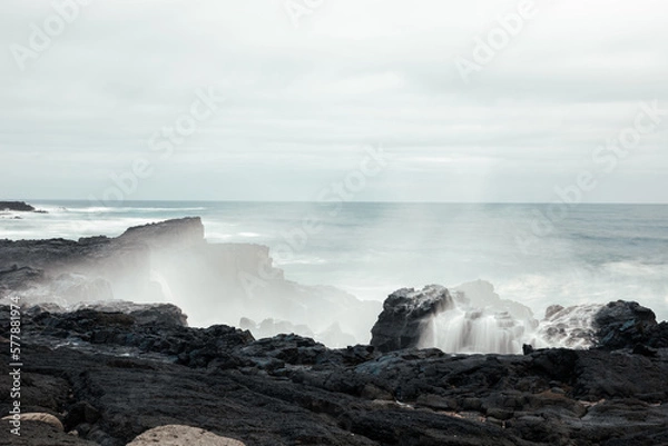 Obraz Long exposure of wave hitting black rocks