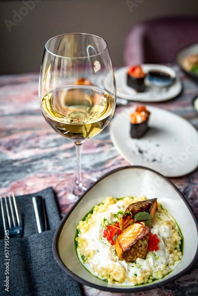 Fototapeta white wine glass with grilled salmon fish fillet with creamy ptitim on table