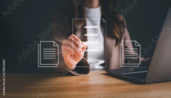 Fototapeta Businesswoman working on laptop with electronics document icons by virtual notebook screen using a stylus pen checking list on a digital tablet. E-document management Paperless workplace concept.
