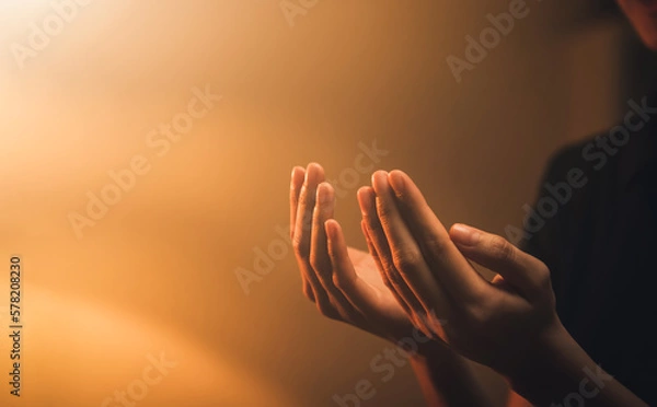 Fototapeta Hand praying on orange light bokeh background.