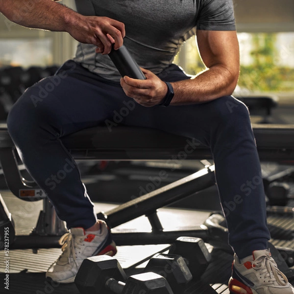 Fototapeta guy is holding a black aluminum can with a drink, in the gym, close-up